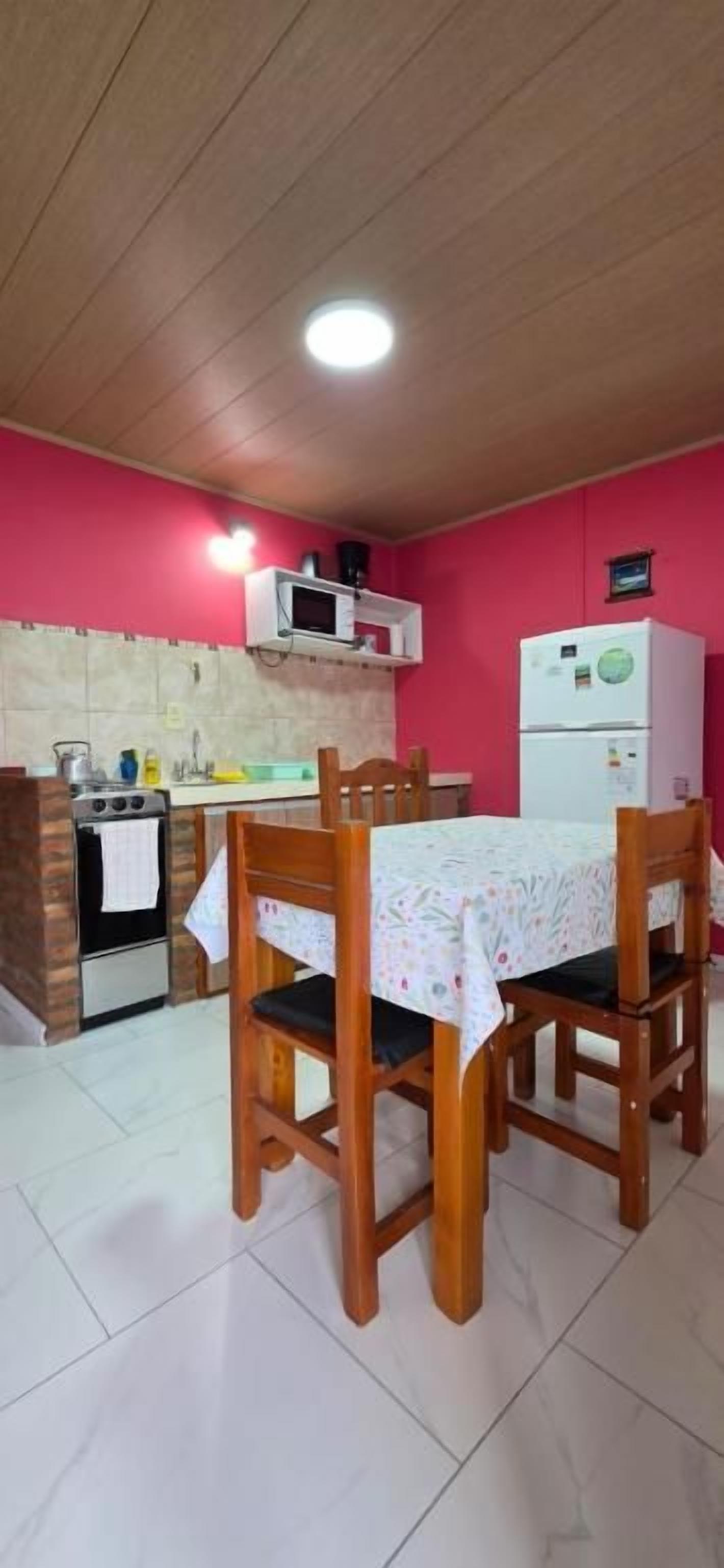 A kitchen with a dining table and chairs, a microwave, a refrigerator, and a stove.