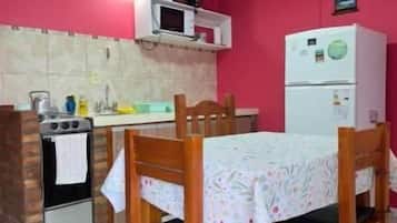 A kitchen with a dining table and chairs, a microwave, a refrigerator, and a stove.