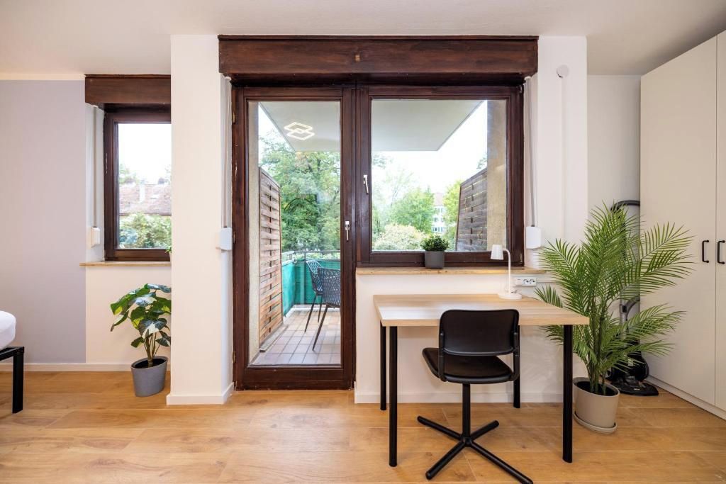 Eine kleine Küche mit Essbereich, eine Schiebeglastür, die auf einen Balkon führt, und ein Blumentopf.