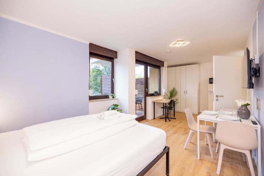 Ein modernes Schlafzimmer mit einem Bett, einem Schreibtisch und einem Stuhl. Ein Fenster und eine Tür sind zu sehen.