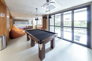A pool table in a modern room with large windows, a white ceiling, and a visible Wi-Fi sign. - Plona by Bhomy (São Paulo)
