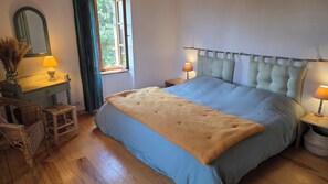 A bedroom with a bed, two bedside tables with lamps, a dresser, a chair, and a window with curtains. - Maison Santoline, a charming home in the heart of the Ardèche. (Nozières)