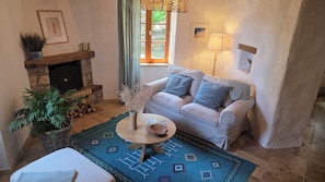 A cozy living room with a fireplace, a sofa, a coffee table, and a patterned rug. - Maison Santoline, a charming home in the heart of the Ardèche. (Nozières)