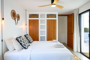 Un dormitorio con cama, ventilador de techo y vistas al exterior.