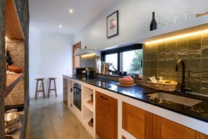Una cocina moderna con encimera negra, armarios de madera y ventana con vistas a la vegetación.