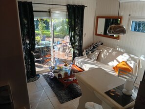 A room with a sofa, a table, and a view of a garden through a sliding door.