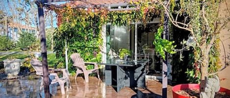 A covered outdoor seating area with a pergola, chairs, and a table.