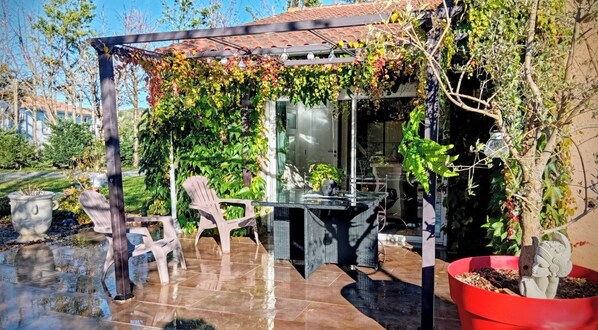 A covered outdoor seating area with a pergola, chairs, and a table.
