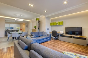 A modern living room with a sectional sofa, a flat-screen TV, and a dining area with a glass table. - Luxury 3-bed With Private Terrace in St Julian s (St. Julian's)