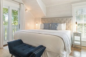 Een slaapkamer met een groot bed, een nachtkastje, een stoel en een raam met zonwering.