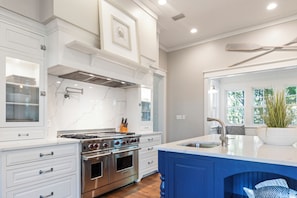 Een moderne keuken met witte kasten, een roestvrijstalen fornuis en een blauwe accentmuur.