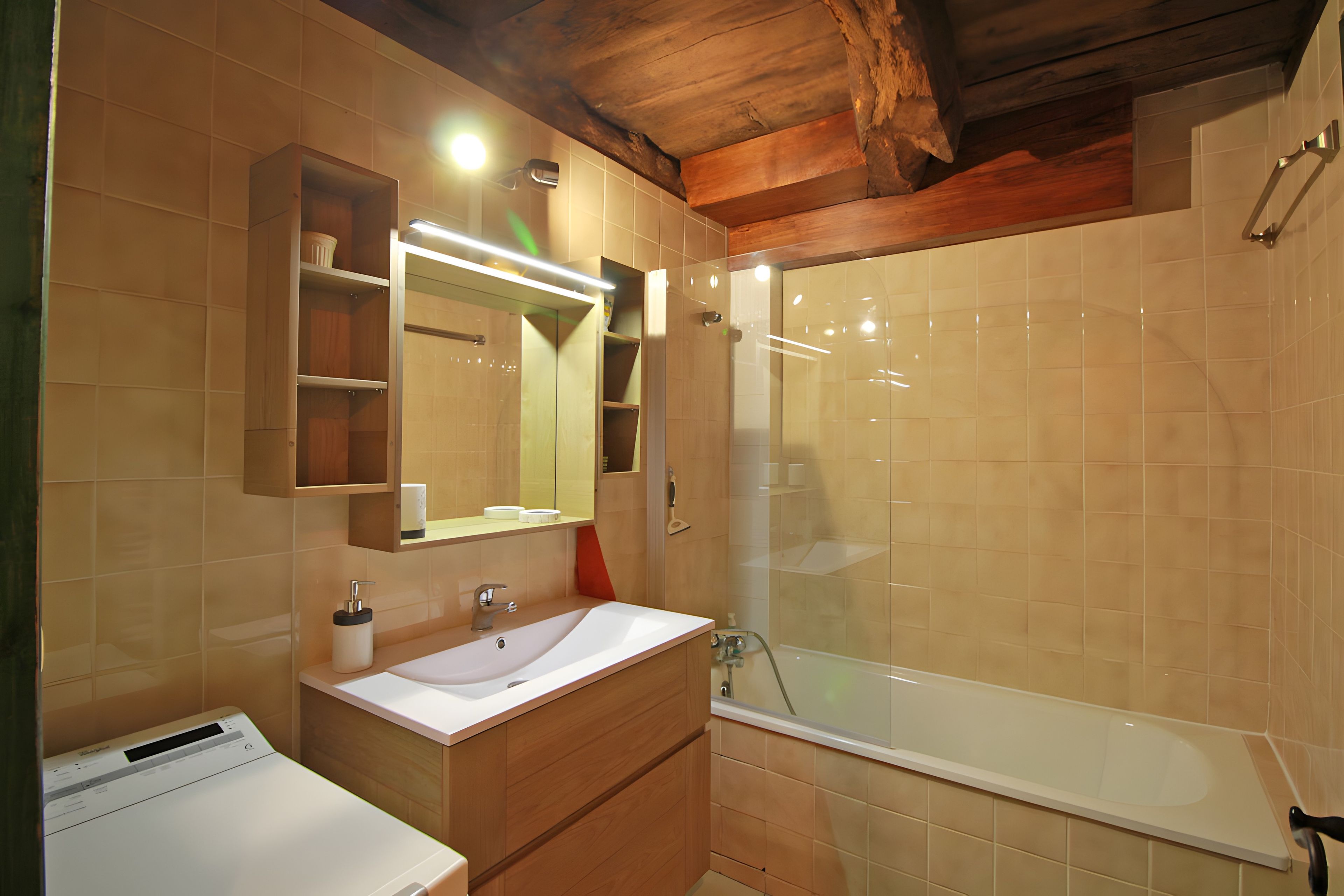 A bathroom with a wooden vanity, a sink, a mirror, and a glass-enclosed shower.
