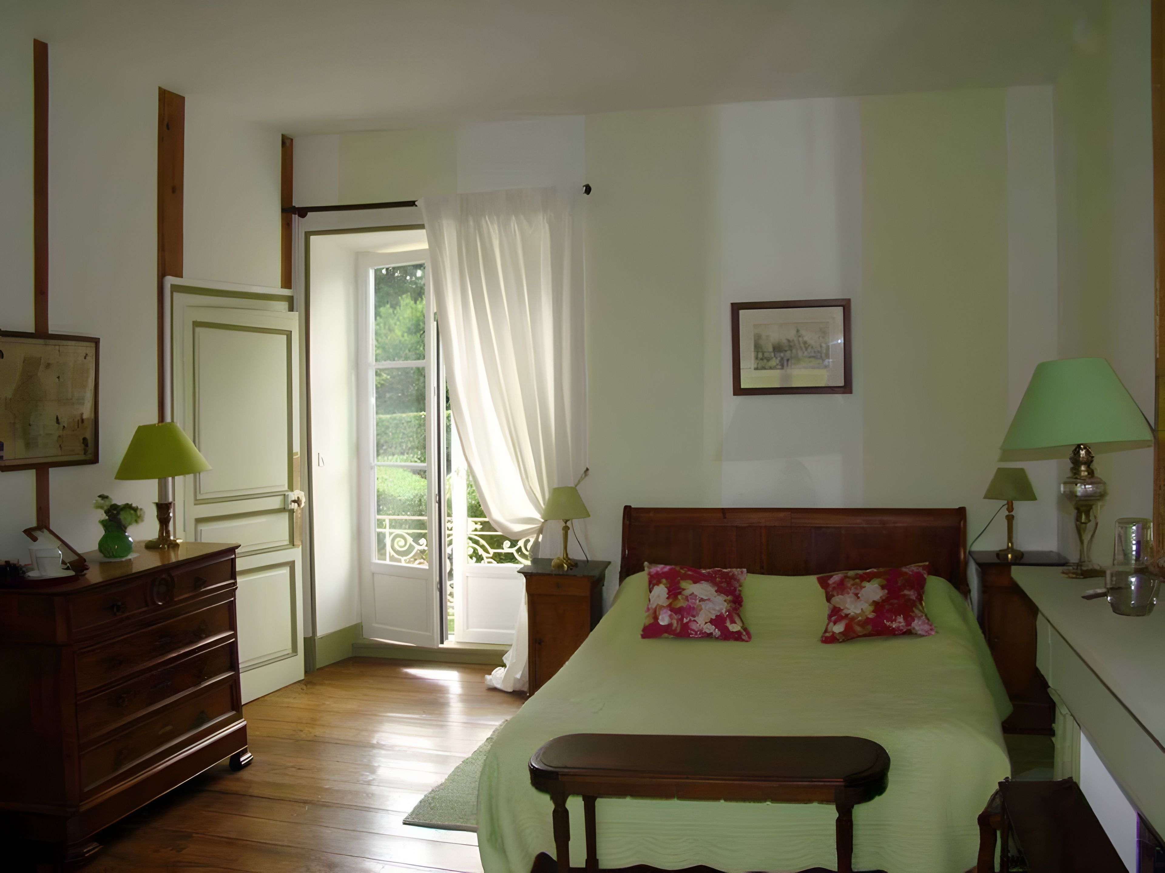 A bedroom with a bed, bedside tables, a dresser, a window with curtains, and a painting on the wall.