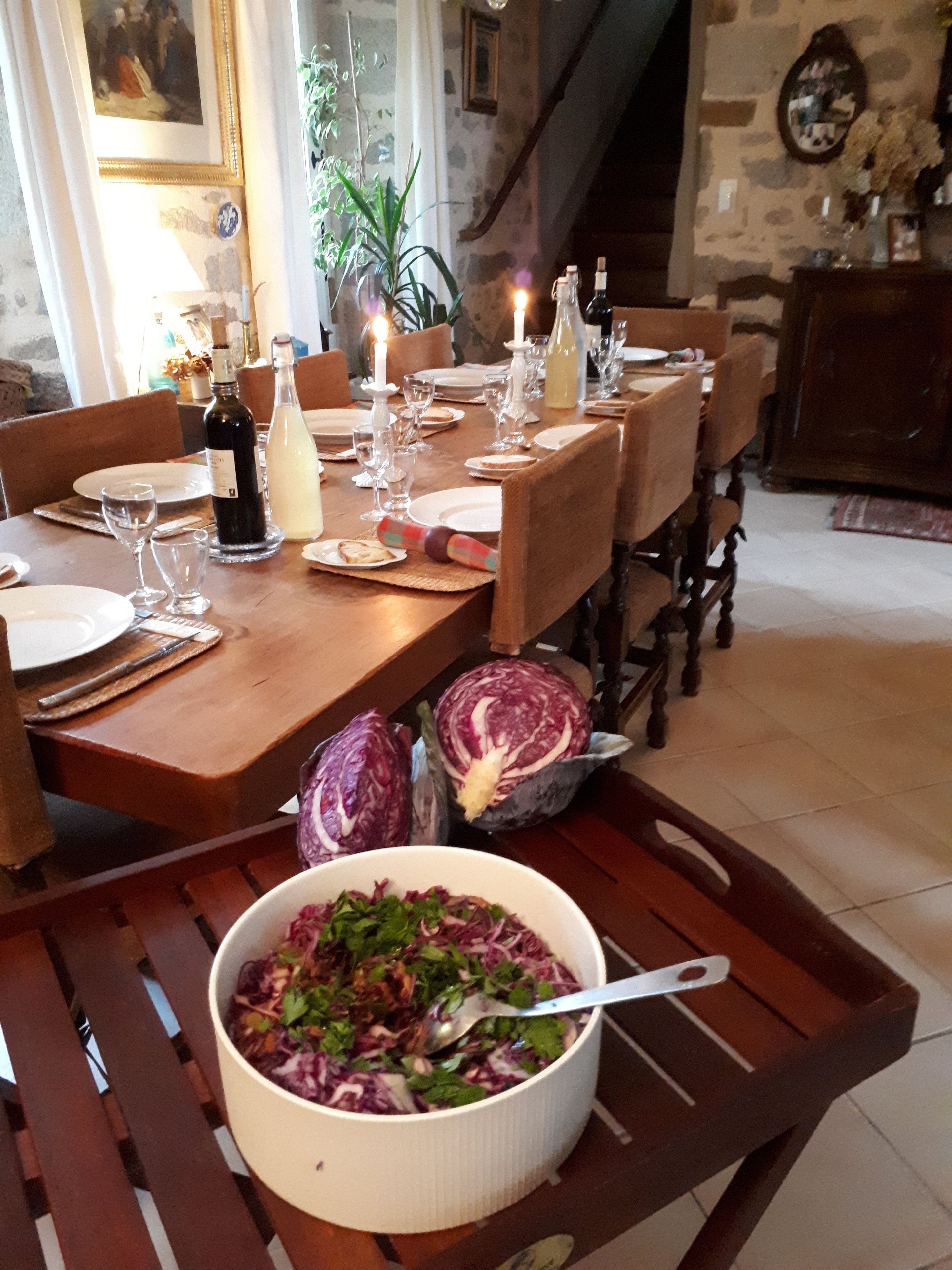 Et spisebord dækket med tallerkener, glas og en salatskål.
