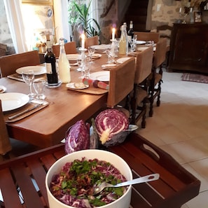 A dining table set with plates, glasses, and bottles, surrounded by chairs.