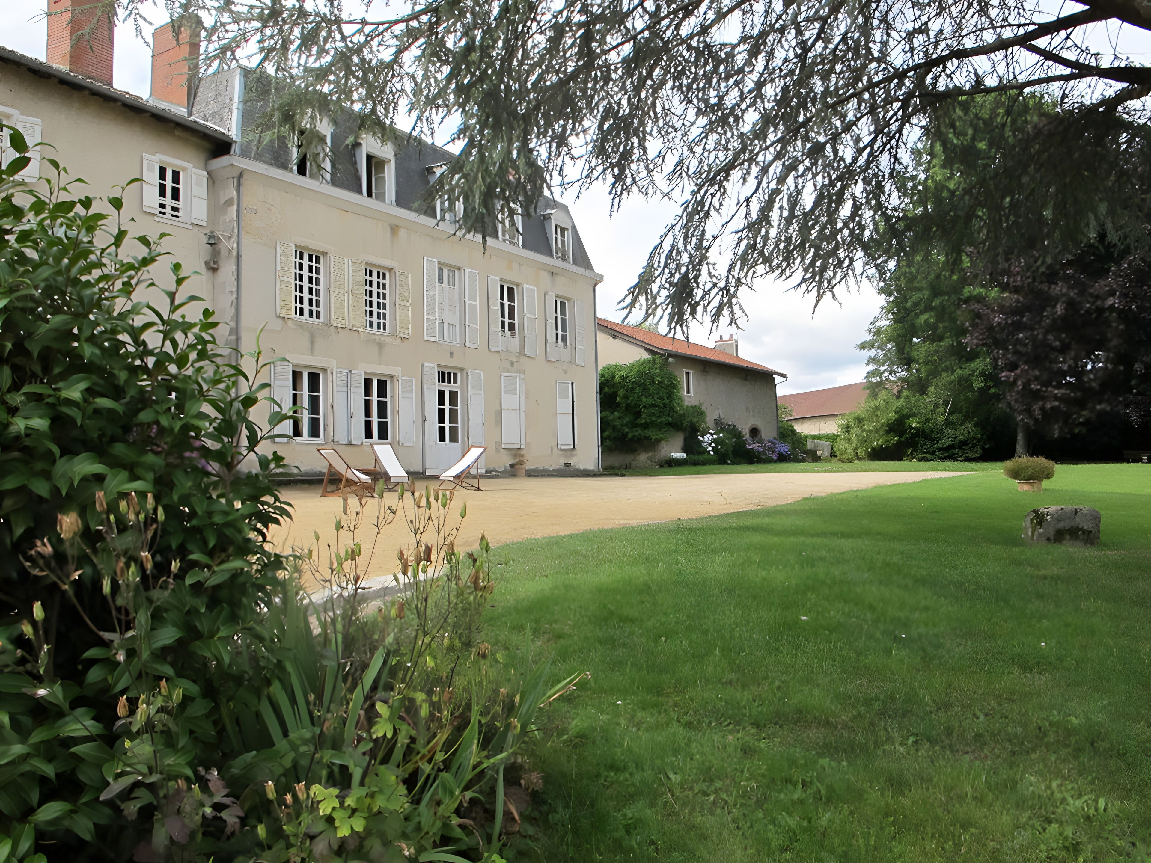 Une grande maison à deux étages, dotée d’une pelouse bien entretenue et d’une allée pavée.