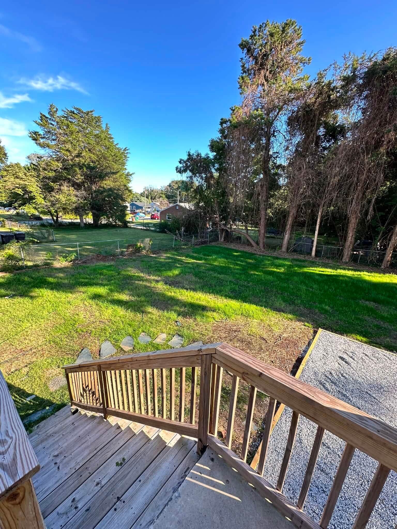 Eine Holzterrasse mit Blick auf einen Rasen und Bäume.