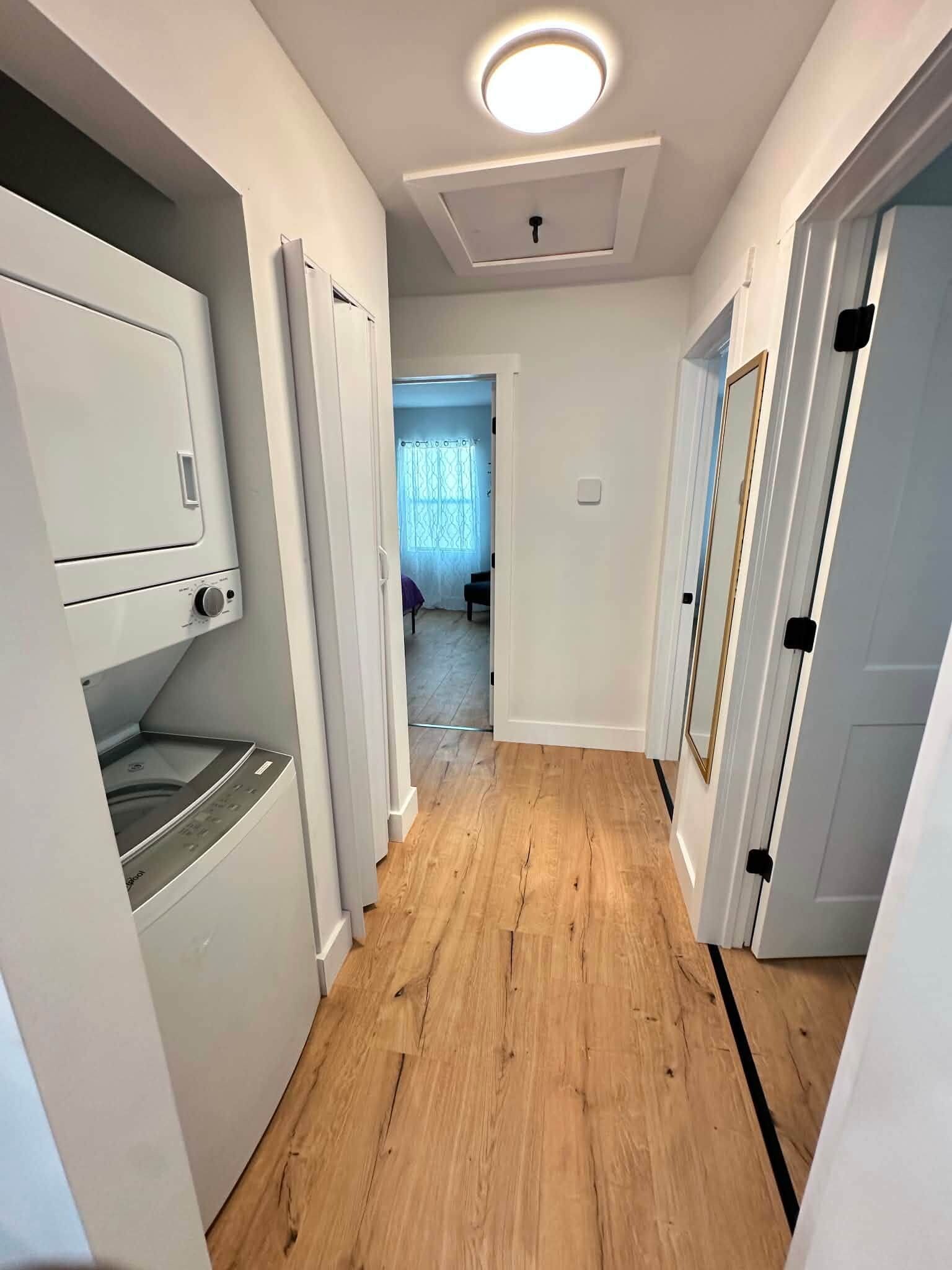A hallway with wooden flooring, white walls, and doors leading to other rooms.