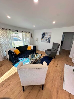 A living room with a sofa, armchair, coffee table, and artwork on the wall. - Eden House: Your cozy retreat in High Point (High Point)