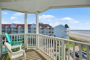 A balcony with a view of beach houses and the ocean. - Seaside Treasure-Top Floor Condo Pool & Beach View (Galveston)