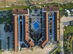 Vista aérea de um hotel com um pátio central, alas simétricas e uma piscina.