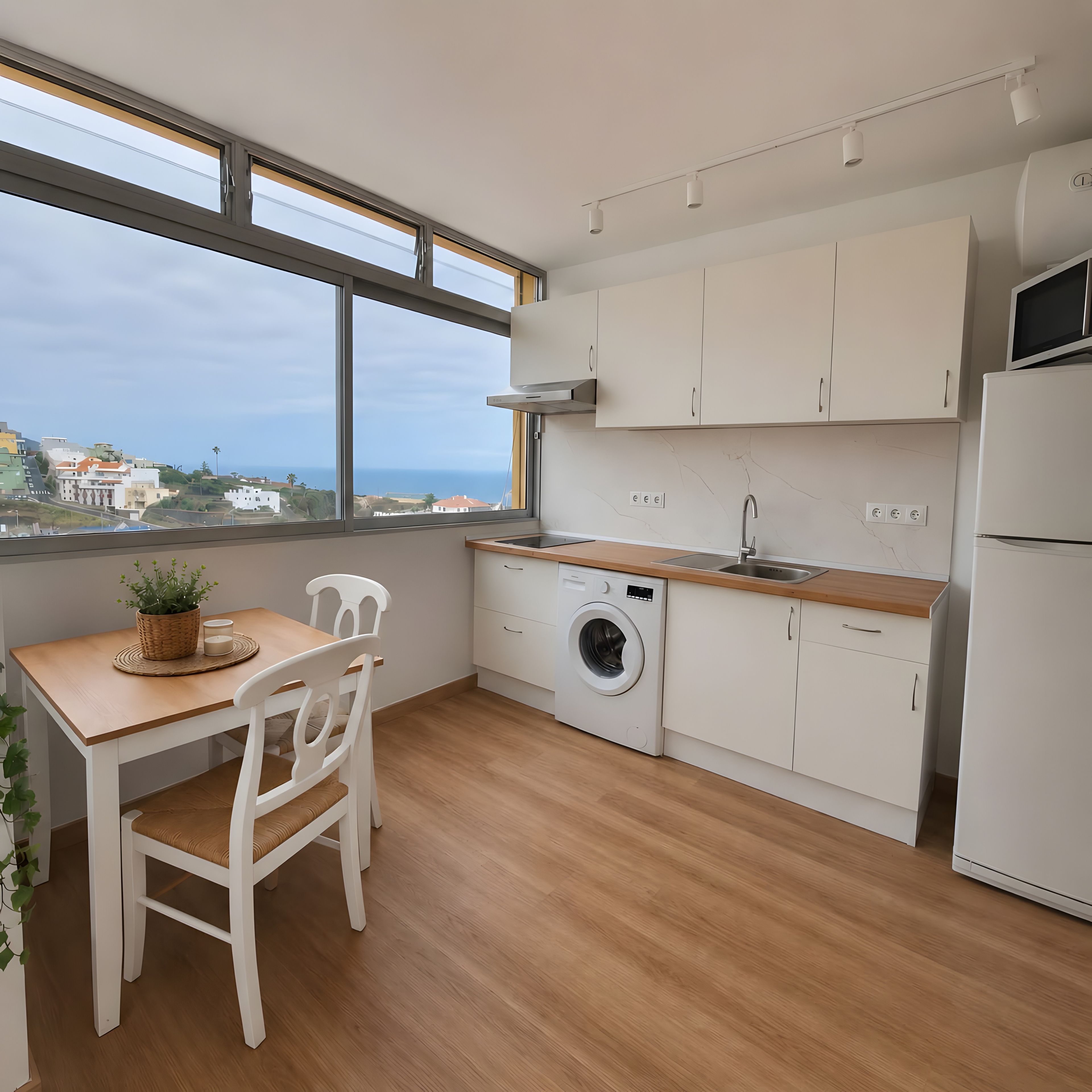 Eine moderne Küche mit Meerblick, einer Waschmaschine und einer Essecke mit Tisch und Stühlen.