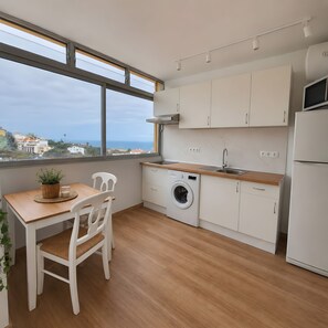 A modern kitchen with a view of the sea, a washing machine, and a dining area with a table and chairs. - Apartment 'Ocean Peak Ático' with Sea View, Mountain View and Wi-Fi (Los Realejos)