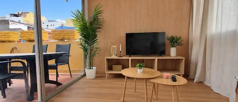 Una sala de estar moderna con un televisor de pantalla plana, muebles de madera y una planta en maceta.