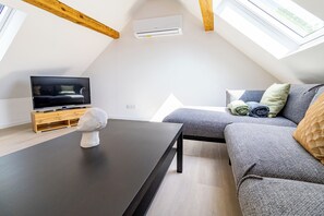 A modern living room with a television, a stone sculpture, a sofa, and a table. - Charming, fully renovated village house (Siersthal)