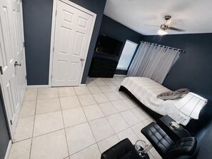 A bedroom with a bed, a desk, a chair, a TV, and a ceiling fan. - 30+ Night 4BR Near Lackland & SeaWorld (San Antonio)