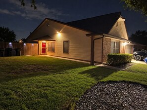 A residential house with a well-maintained lawn, a red door, and a garage. - 30+ Night 4BR Near Lackland & SeaWorld (San Antonio)