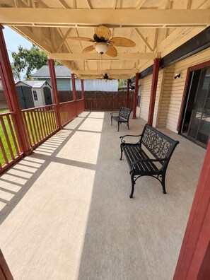 A covered porch with two benches, a ceiling fan, and a view of the backyard. - 30+ Night 4BR Near Lackland & SeaWorld (San Antonio)