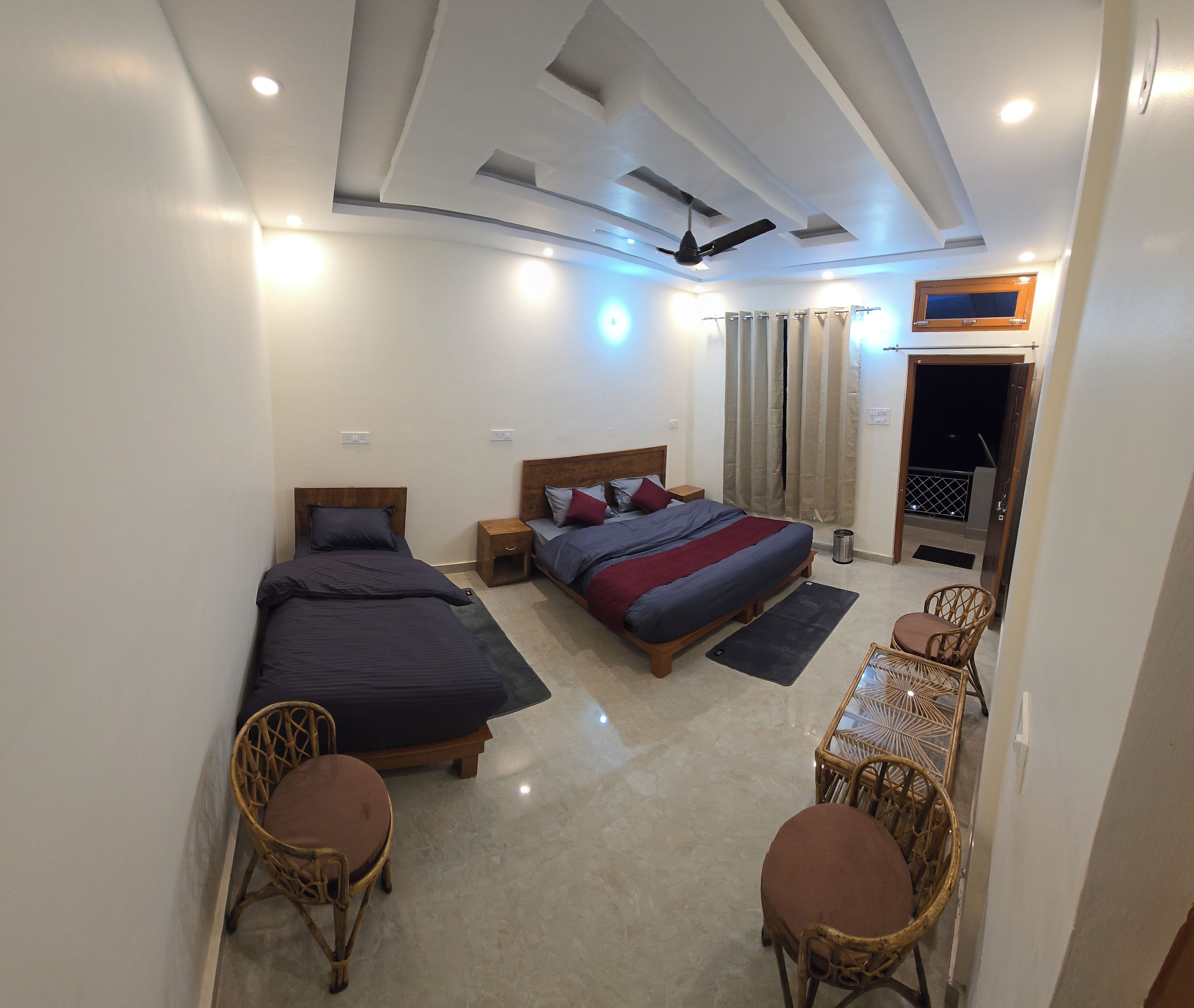 A bedroom with two beds, a ceiling fan, and a small table with chairs.