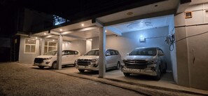 Un área de estacionamiento techada con tres coches aparcados bajo una estructura con tragaluces.