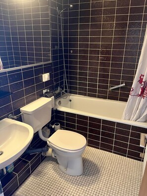 Kylpyhuone, jossa on wc, pesuallas ja kylpyamme.