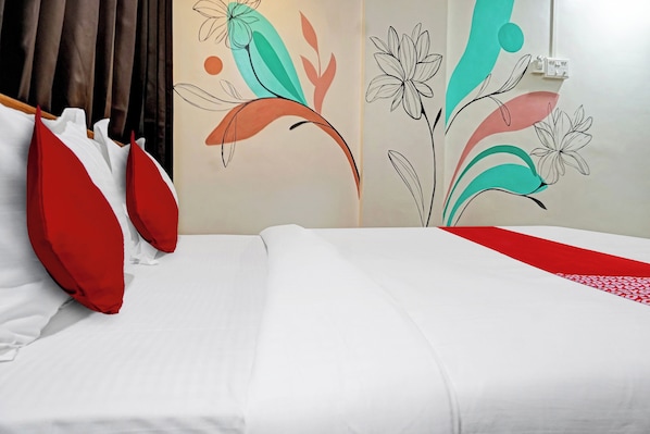 A hotel room with a bed, red and white pillows, and a wall with abstract floral wall art. - Hotel O Aru Sai (Pune)