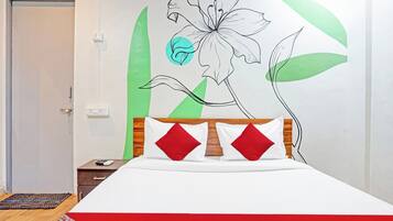 Una camera da letto con un letto, un comodino, una parete con un murale floreale e una porta.