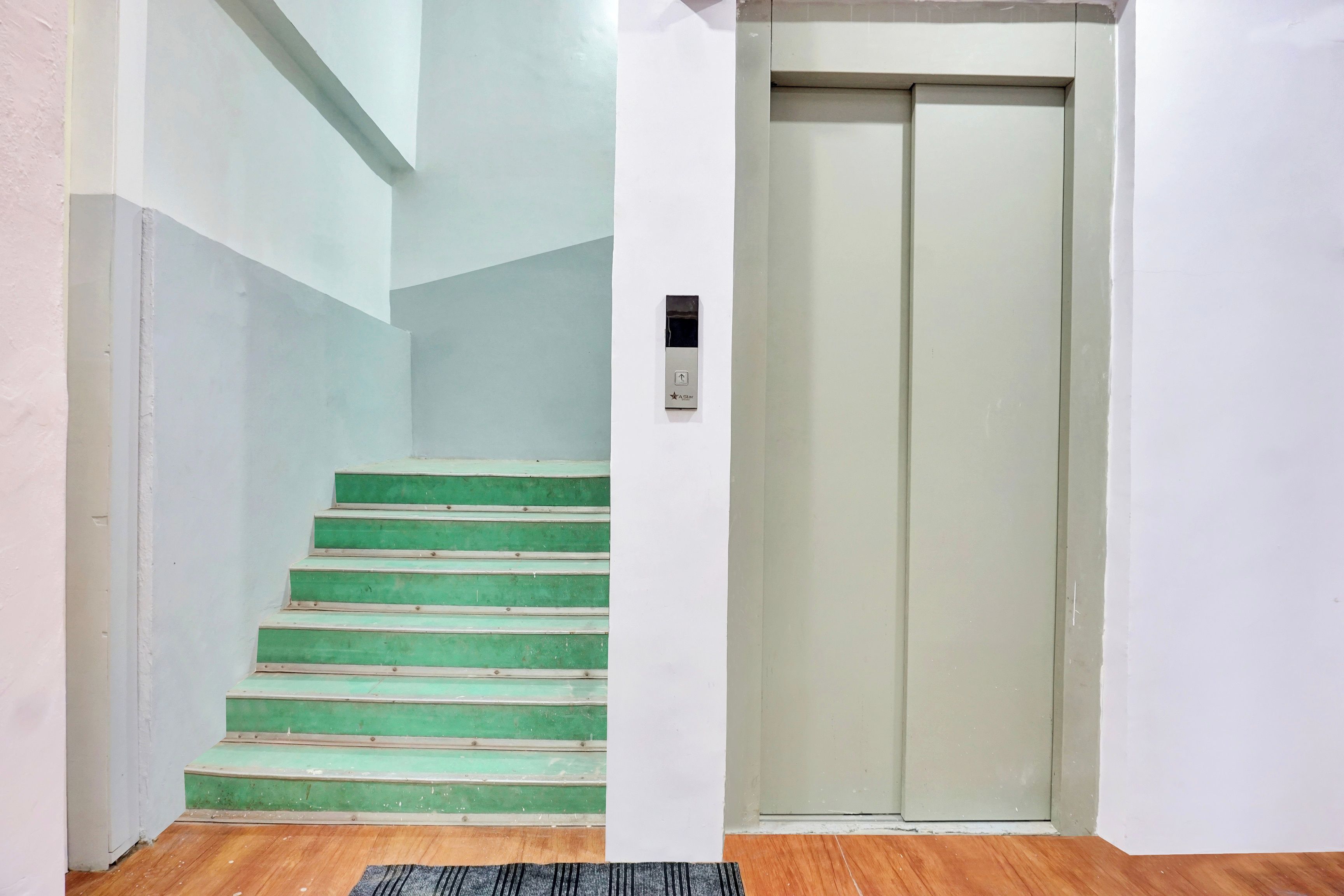 A staircase with green steps leading to a door with a control panel.