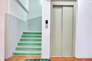 A staircase with green steps leading to a door with a control panel. - Hotel O Aru Sai (Pune)