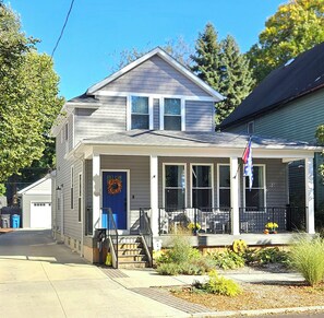 A two-story house with a front porch, a garage, and a flag on the right side. - Stylish Ohio City Retreat Near W25, Gordon Square, Edgewater Beach & Restaurants (Cleveland)