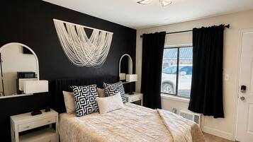 Un dormitorio moderno con una cama grande, mesitas de noche, una silla y vistas al exterior.