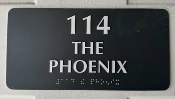 Una placa de dirección negra con letras blancas sobre una pared texturizada.