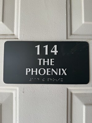 A black address plaque with white lettering on a textured wall.
