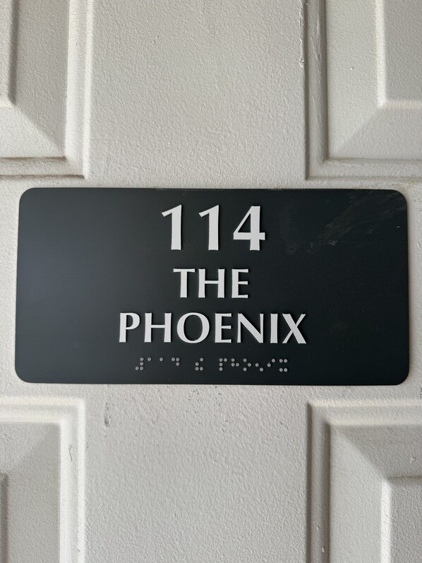 A black address plaque with white lettering on a textured wall.
