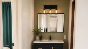 Un pasillo estrecho con un mueble de madera oscuro, un lavabo blanco y un espejo encima.