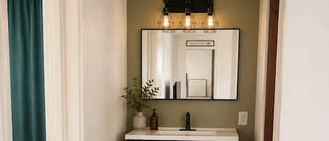 Un pasillo estrecho con un mueble de madera oscuro, un lavabo blanco y un espejo encima.