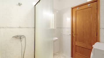 Un baño con ducha, lavamanos y puerta de madera.