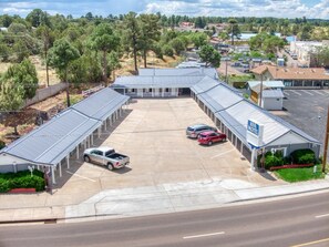 A motel with a covered parking area, multiple rooms, and a sign indicating the name.