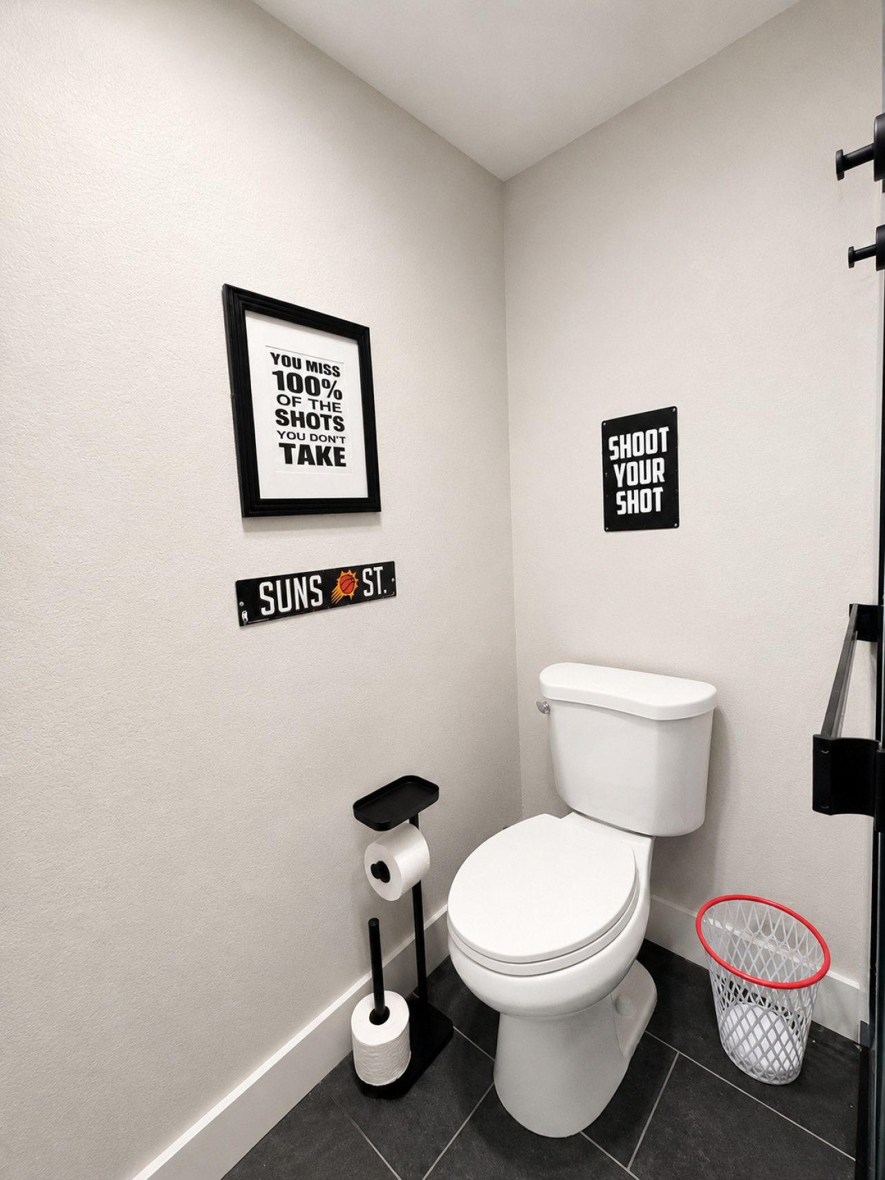 A modern bathroom with a toilet, a bidet, a toilet paper holder, and a trash can.
