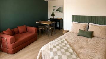A room with a bed, a sofa, a dining table, and chairs.